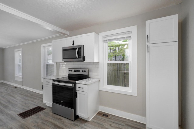 kitchen featuring appliances with stainless steel finishes, beam ceiling, baseboards, and white cabinets