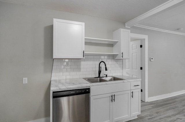kitchen featuring stainless steel dishwasher, a sink, tasteful backsplash, baseboards, and beam ceiling