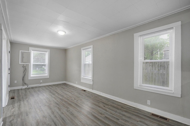 unfurnished room featuring crown molding, healthy amount of natural light, wood finished floors, and baseboards
