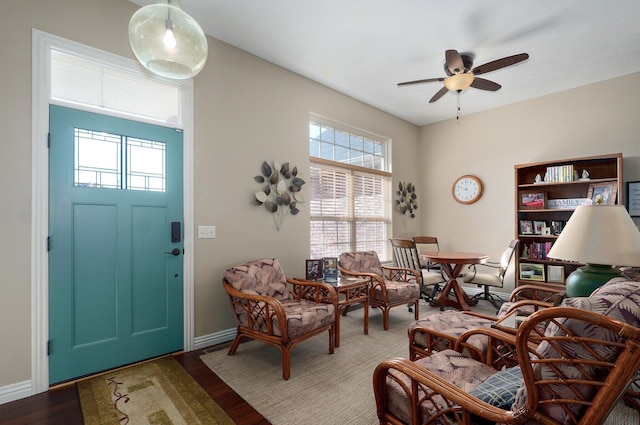 living area featuring a ceiling fan, wood finished floors, and baseboards