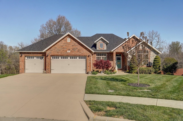 traditional home featuring brick siding, an attached garage, concrete driveway, a front lawn, and roof with shingles