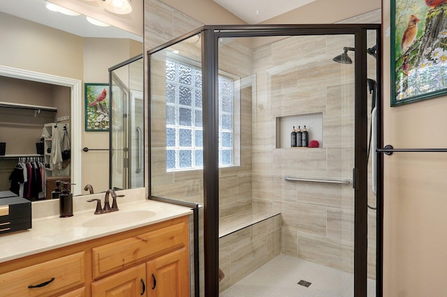 bathroom featuring a stall shower, vanity, and a walk in closet