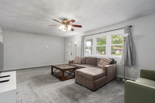 carpeted living area with ceiling fan and baseboards