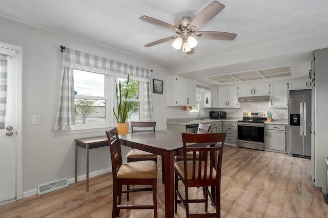 dining area featuring light wood-type flooring, a ceiling fan, and baseboards