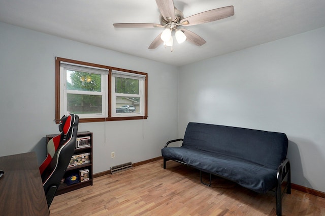 living area featuring light wood finished floors, baseboards, and ceiling fan
