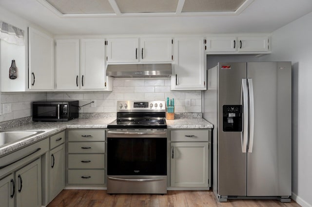 kitchen with stainless steel appliances, under cabinet range hood, dark wood-style flooring, decorative backsplash, and light countertops