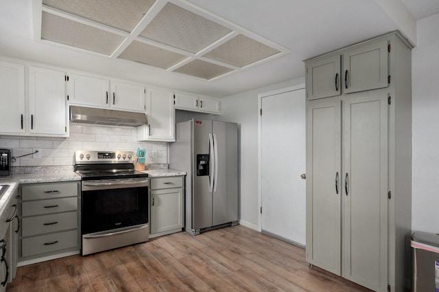 kitchen with stainless steel appliances, under cabinet range hood, gray cabinets, and decorative backsplash