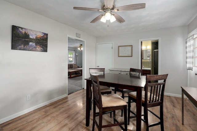dining space with a ceiling fan, wood finished floors, and baseboards