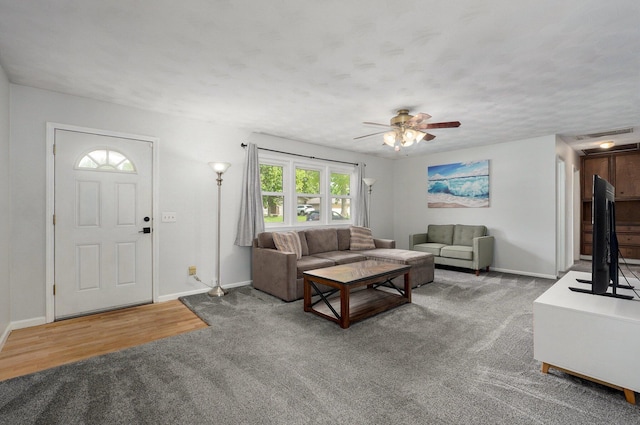 living room featuring carpet, baseboards, and a ceiling fan