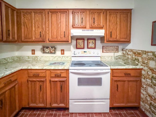 kitchen featuring under cabinet range hood, white electric range, light countertops, and brown cabinetry