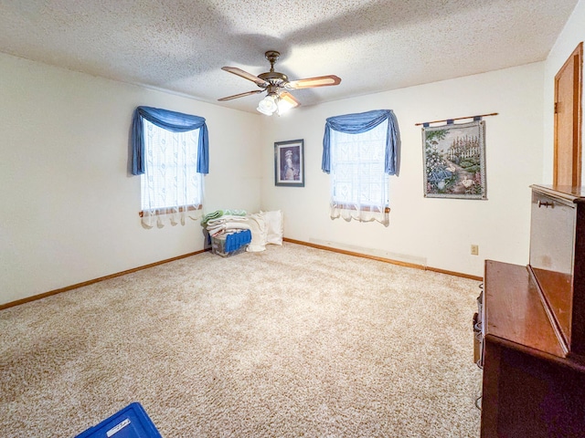 unfurnished bedroom with carpet, baseboards, ceiling fan, and a textured ceiling