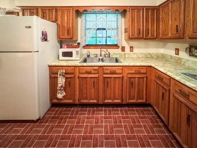 kitchen with white appliances, a sink, brick patterned flooring, light countertops, and brown cabinetry