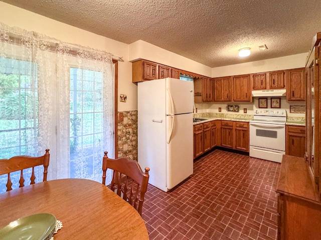 kitchen featuring white appliances, under cabinet range hood, brown cabinetry, light countertops, and brick patterned floors