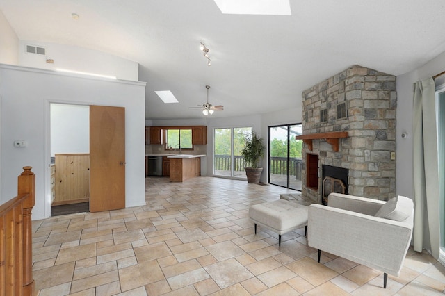 living area with a skylight, lofted ceiling, ceiling fan, and a fireplace