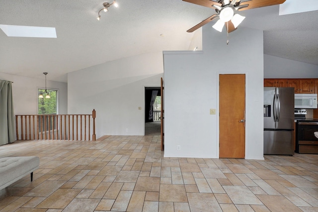 kitchen featuring appliances with stainless steel finishes, lofted ceiling, a ceiling fan, open floor plan, and a skylight