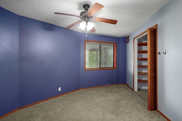 carpeted empty room featuring baseboards and a ceiling fan