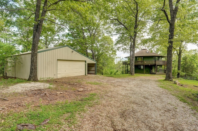 view of yard featuring a garage, a deck, an outbuilding, and driveway