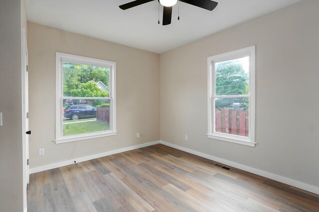 empty room featuring a ceiling fan, plenty of natural light, wood finished floors, and baseboards