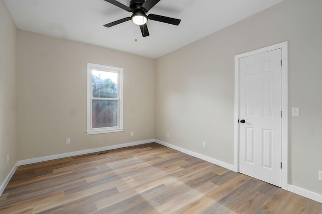 empty room with ceiling fan, light wood-type flooring, and baseboards