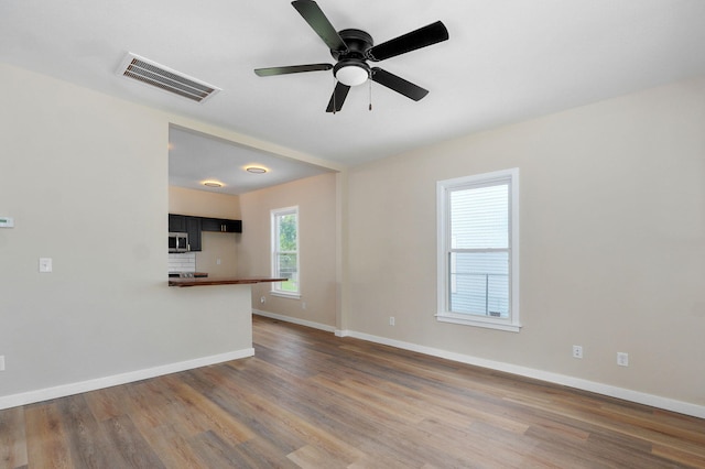 unfurnished living room with wood finished floors, baseboards, and ceiling fan