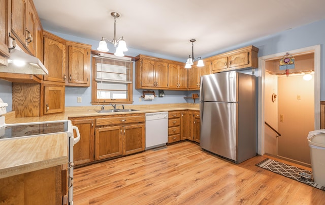 kitchen with white appliances, brown cabinets, a sink, a chandelier, and light countertops