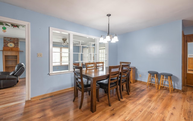 dining room featuring light wood-style floors, a chandelier, baseboards, and ceiling fan