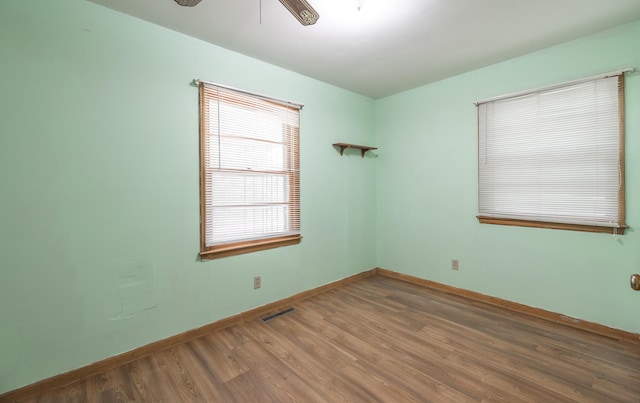 spare room featuring wood finished floors, a ceiling fan, and baseboards