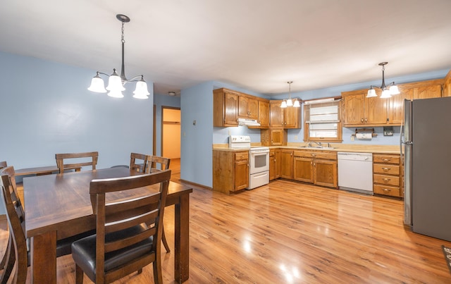 kitchen with white appliances, a sink, a chandelier, and light countertops