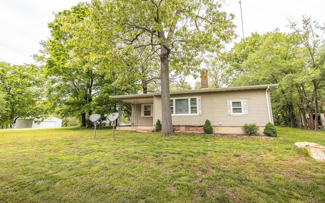 back of house with a chimney, a lawn, and an outbuilding