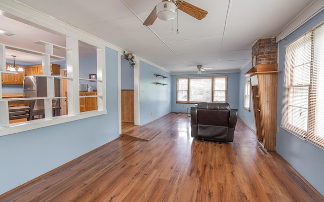sitting room featuring ceiling fan, wood finished floors, and ornamental molding
