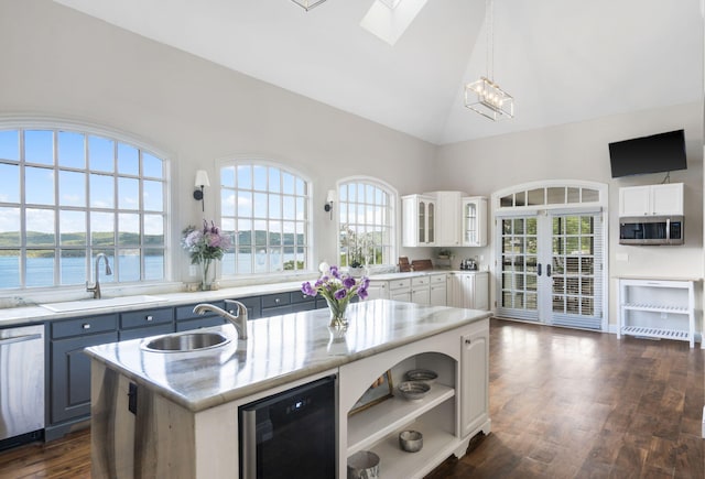 kitchen featuring a sink, stainless steel appliances, wine cooler, healthy amount of natural light, and high vaulted ceiling