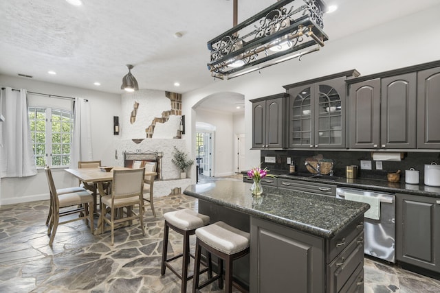 kitchen featuring dishwasher, arched walkways, stone floors, healthy amount of natural light, and recessed lighting