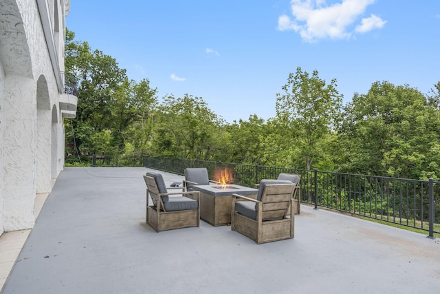 view of patio / terrace with an outdoor fire pit and a view of trees