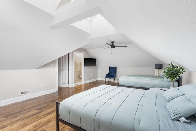 bedroom featuring baseboards, wood finished floors, a ceiling fan, a skylight, and vaulted ceiling