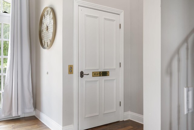 doorway featuring baseboards and wood finished floors
