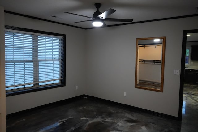 spare room featuring a ceiling fan, concrete flooring, baseboards, and ornamental molding