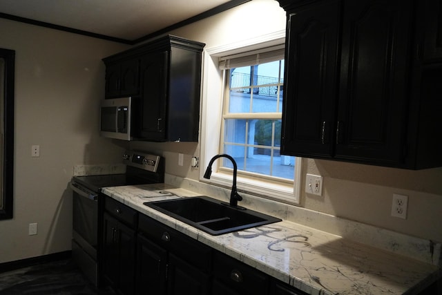 kitchen with stainless steel appliances, a sink, dark cabinets, light countertops, and ornamental molding