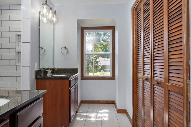 full bathroom with two vanities, baseboards, tile patterned flooring, and a closet