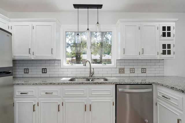 kitchen with appliances with stainless steel finishes, white cabinets, backsplash, and decorative light fixtures