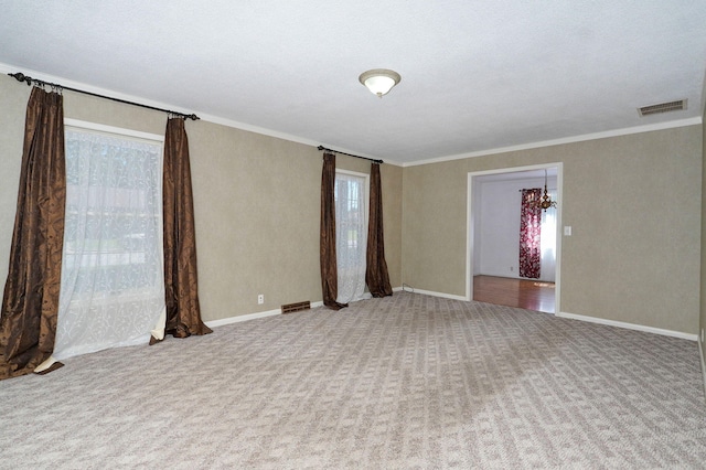 carpeted empty room featuring crown molding and baseboards