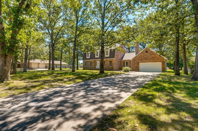 view of front facade with a garage, a front yard, concrete driveway, a chimney, and stone siding
