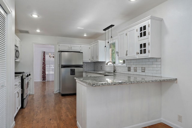 kitchen with stainless steel appliances, a peninsula, a sink, light stone countertops, and tasteful backsplash