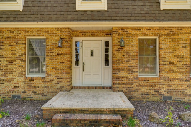 property entrance with crawl space, roof with shingles, and brick siding
