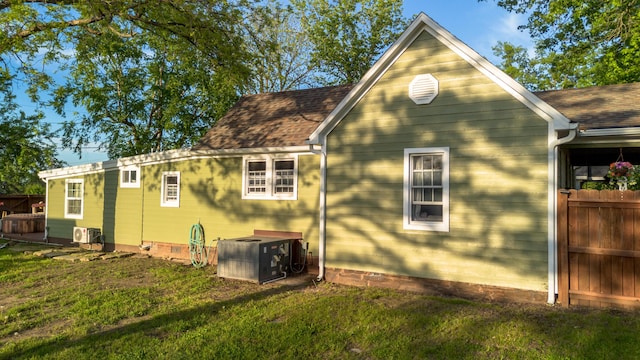 111 W Olive St, El Dorado Springs, MO 64744 - view of side of property featuring a lawn, central AC, roof with shingles, and crawl space