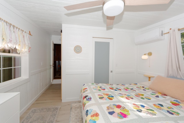 111 W Olive St, El Dorado Springs, MO 64744 - bedroom with an AC wall unit, light wood-style floors, a decorative wall, a closet, and a ceiling fan
