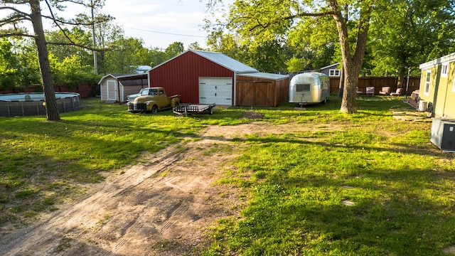111 W Olive St, El Dorado Springs, MO 64744 - view of yard with driveway, an outdoor structure, a storage shed, a detached garage, and an outdoor pool