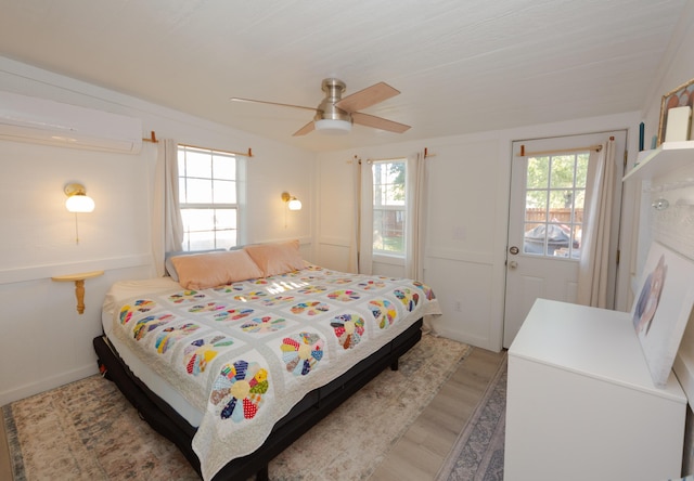 111 W Olive St, El Dorado Springs, MO 64744 - bedroom with light wood-type flooring, a wall unit AC, and ceiling fan