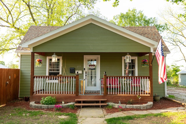 111 W Olive St, El Dorado Springs, MO 64744 - bungalow featuring a porch, roof with shingles, and fence