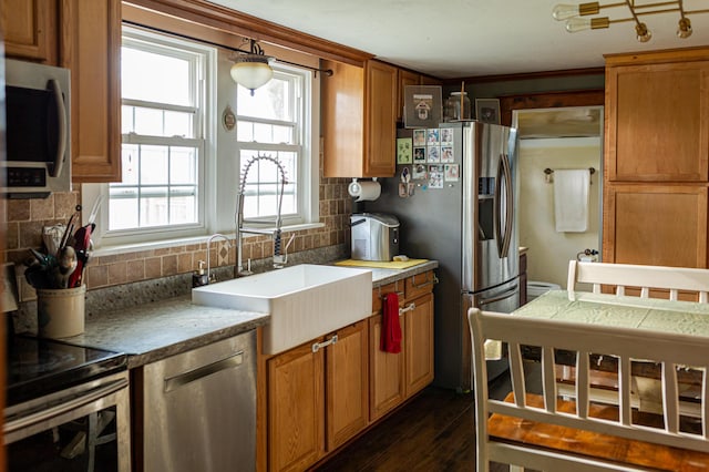 111 W Olive St, El Dorado Springs, MO 64744 - kitchen featuring appliances with stainless steel finishes, a sink, tasteful backsplash, dark wood finished floors, and brown cabinets