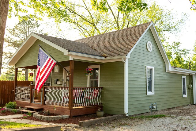 111 W Olive St, El Dorado Springs, MO 64744 - view of side of property featuring roof with shingles and covered porch